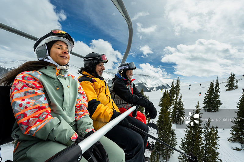 闭着眼睛享受冷风，与朋友乘坐滑雪缆车的女人图片素材