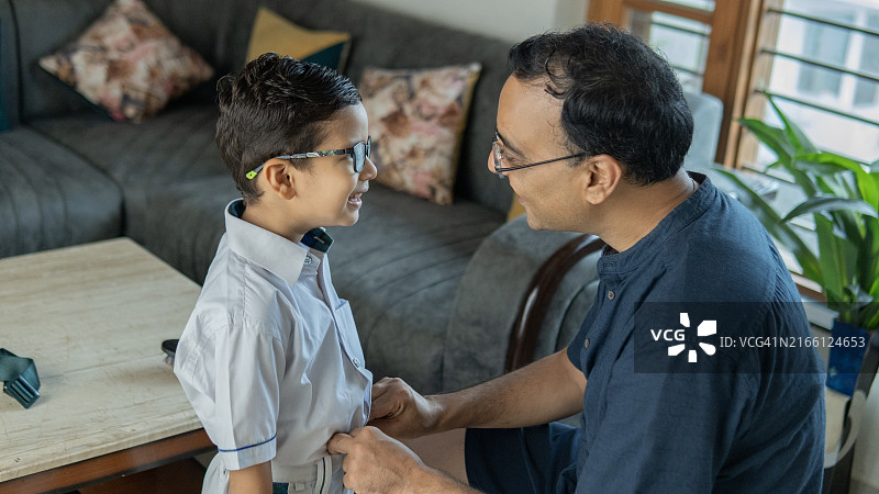 男人在家帮助儿子穿上学服装图片素材