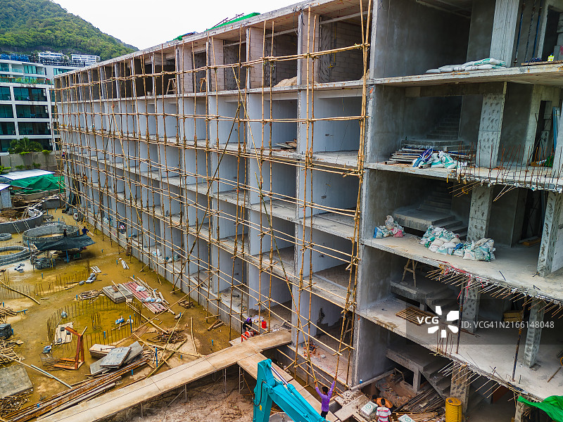 大型建筑工地，游泳池和建筑物周围的脚手架，机械与工人混杂。图片素材