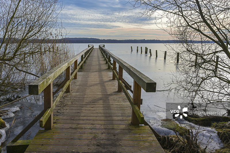 拉策堡冰冻湖上的木制人行桥码头，德国北部早春的冬日景色图片素材