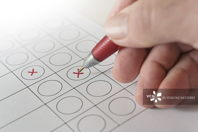 手持红色圆珠笔在选票上打叉，投票选举概念图片素材