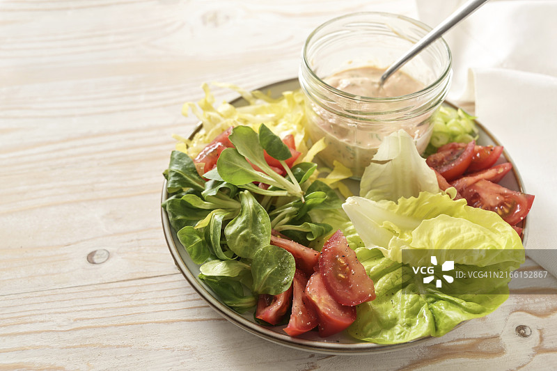 白色木桌上玻璃罐中的千岛酱生菜番茄沙拉图片素材