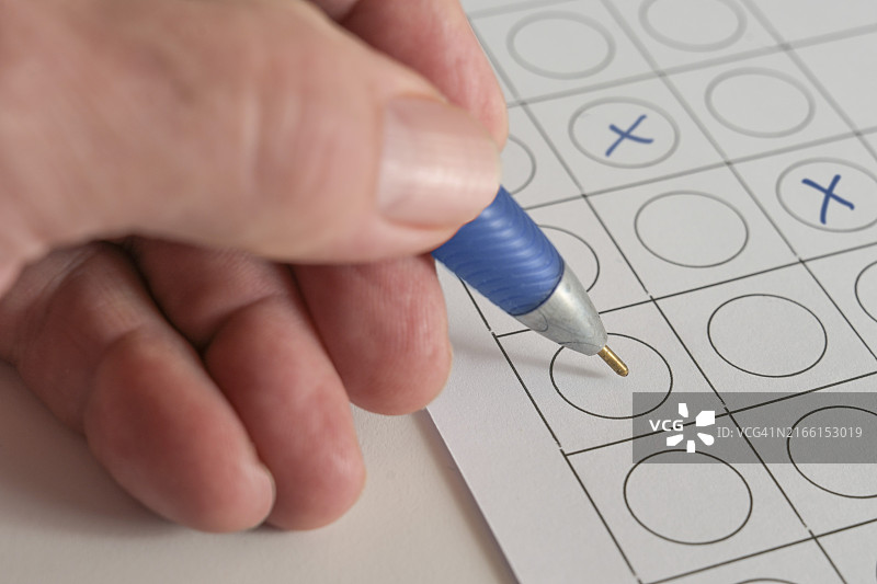 手持蓝色笔在纸上表格中打叉，用于商业应用测试或选举投票的概念，留白，选定焦点，窄景深图片素材