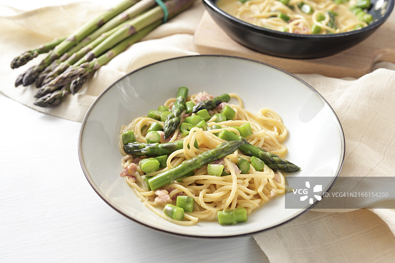 配芦笋的意式培根蛋面，配料和餐巾在白色桌子上图片素材