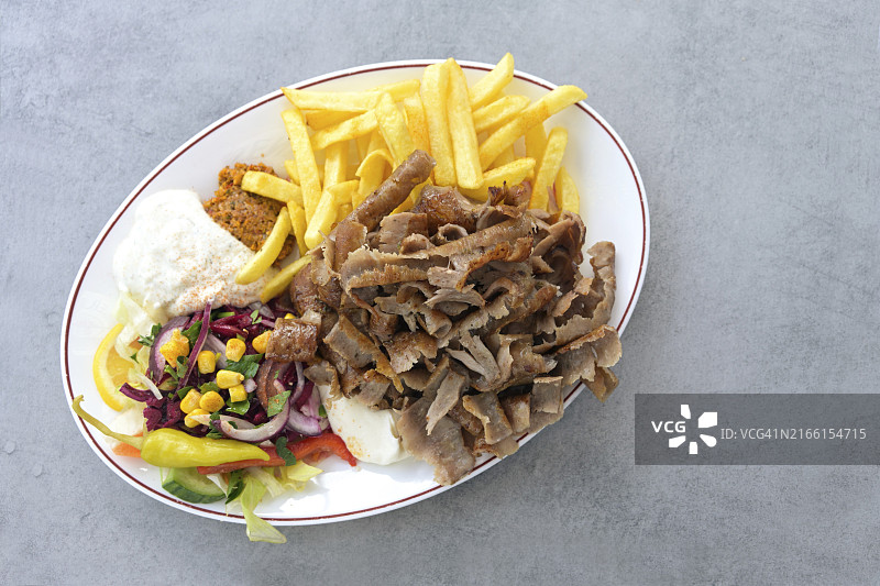 土耳其烤肉：椭圆盘盛放的肉片、沙拉、薯条和酸奶蘸酱图片素材