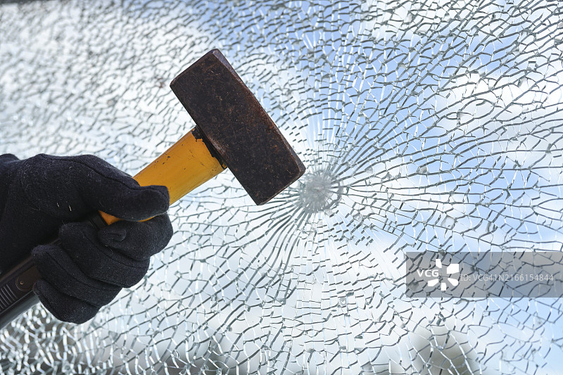 男人用重锤敲打安全玻璃窗户图片素材