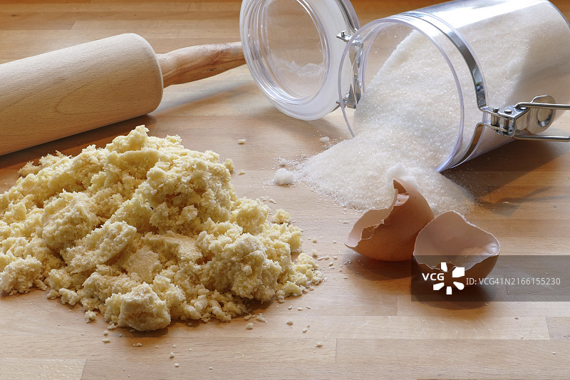 在家烘焙场景，木桌上有擀面杖、面团、糖和空蛋壳图片素材