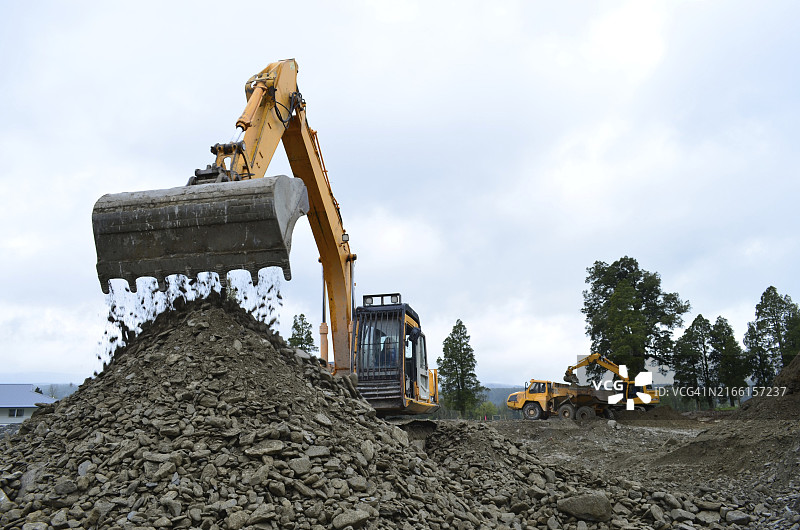 在新西兰西部的建筑工地，挖掘机正在填充一辆自卸卡车图片素材