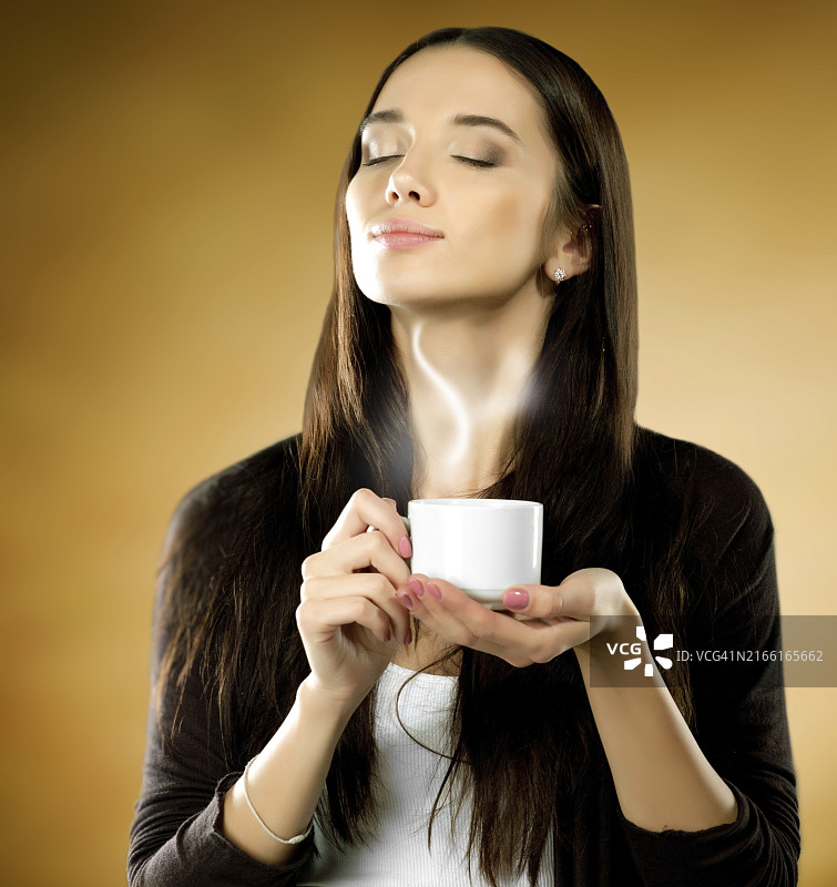 棕色背景下手拿咖啡杯的女人图片素材