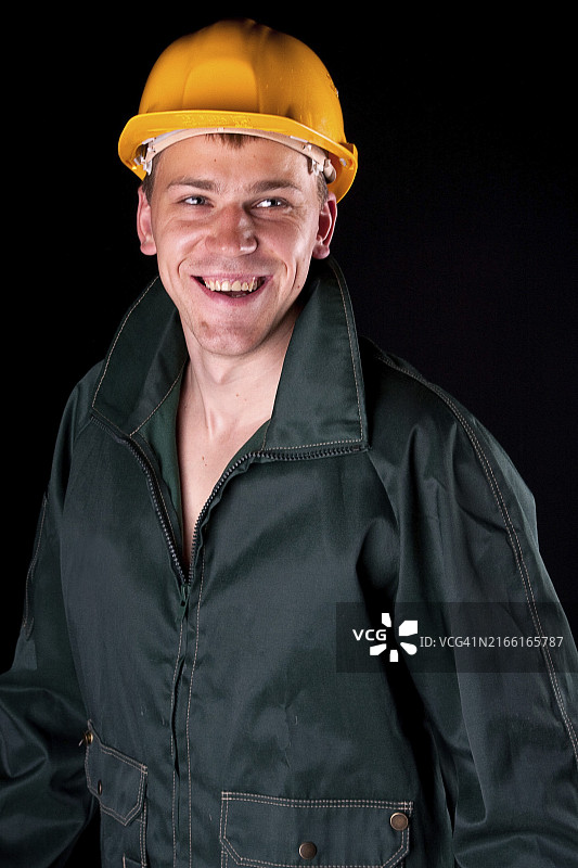 戴黄色安全帽的工人。黑色背景，工作室拍摄图片素材