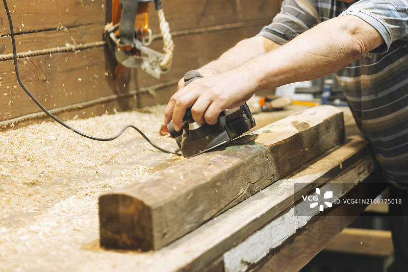木匠在工作室用电动刨床刨木梁图片素材