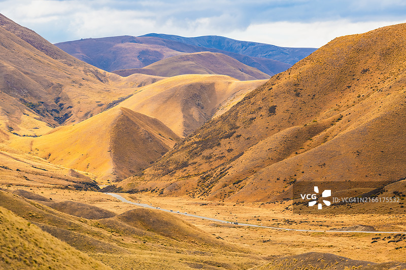 新西兰林迪斯山口地区的金色山丘和蜿蜒道路图片素材