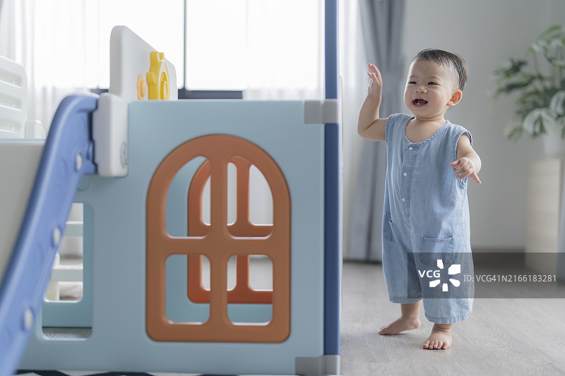 在塑料玩具屋里玩耍的亚洲男婴图片素材