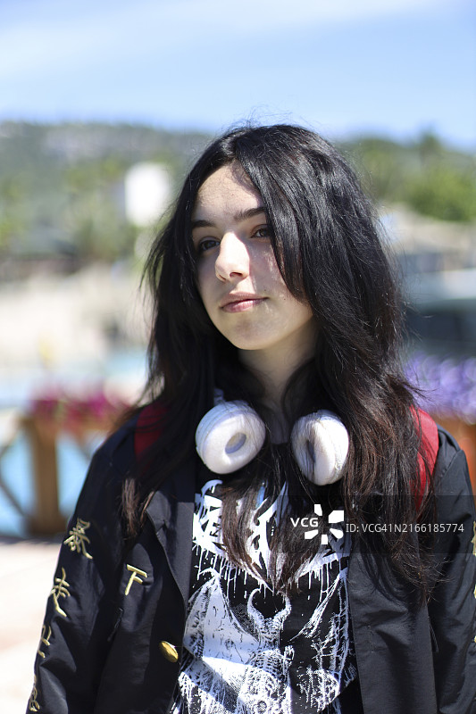 戴着耳机在充满活力的户外休闲区享受阳光明媚一天的年轻女人图片素材