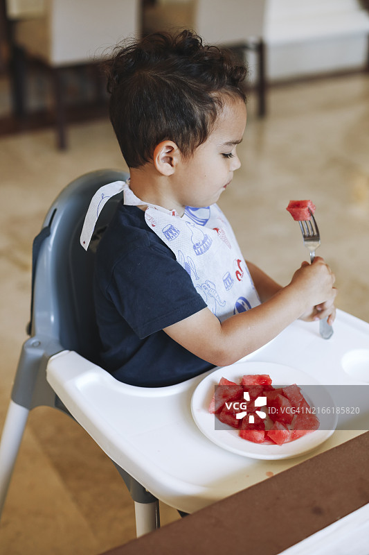午餐时间，在咖啡馆的高脚椅上享用西瓜的幼儿图片素材
