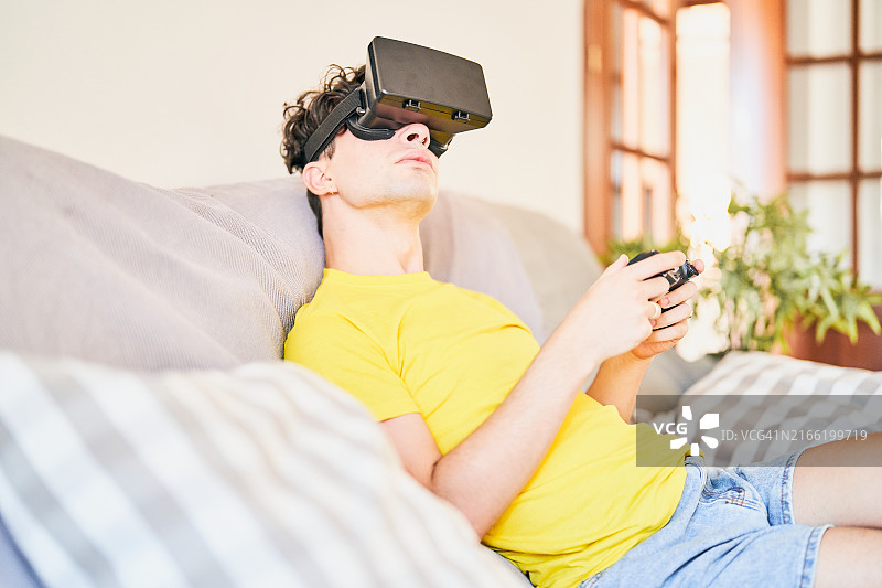 年轻男人戴VR眼镜在沙发上放松图片素材