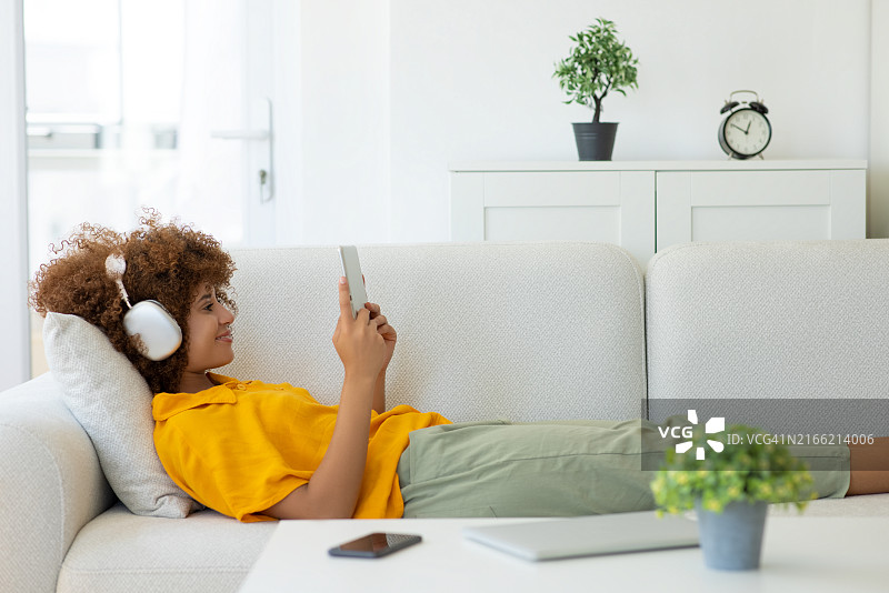 年轻女人在沙发上使用平板电脑图片素材