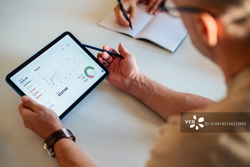 商人开会期间在平板电脑上分析财务数据图片素材