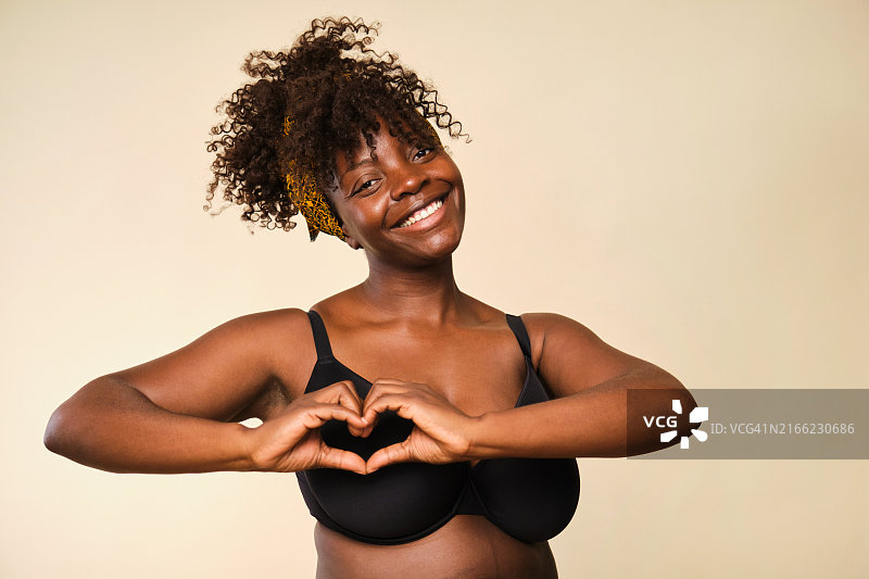 面带微笑的黑人女性用手在胸前比心图片素材