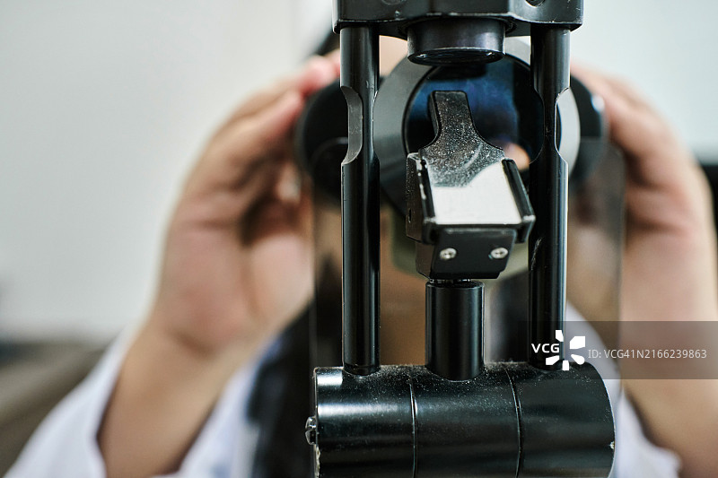 验光师使用检眼镜为患者检查眼睛图片素材