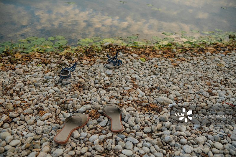 湖边鹅卵石滩上的儿童和女士鞋子图片素材