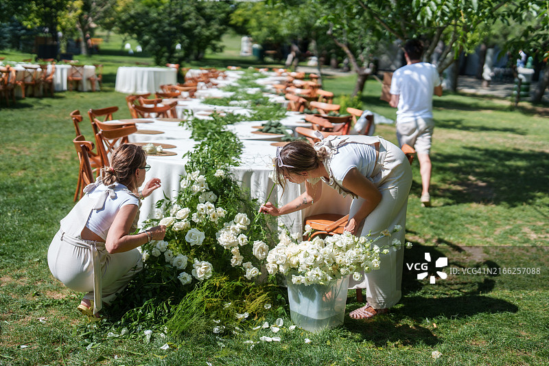 婚礼策划团队在餐桌花环上装饰鲜花图片素材