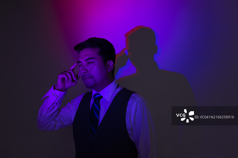 霓虹灯下头痛的年长男人图片素材