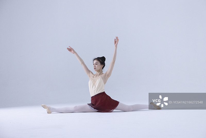坐在地上练习伸展的年轻芭蕾舞演员图片素材
