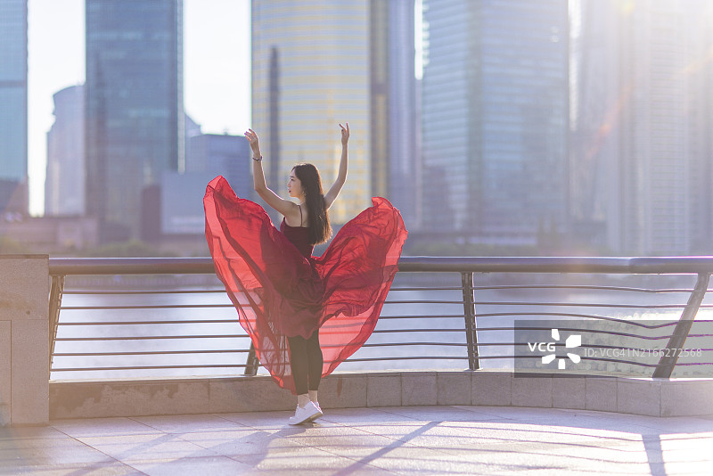 清晨在上海外滩跳舞的红裙年轻漂亮女人图片素材