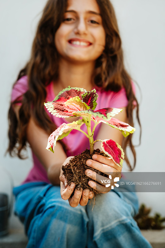 微笑的女孩手捧彩色植物图片素材