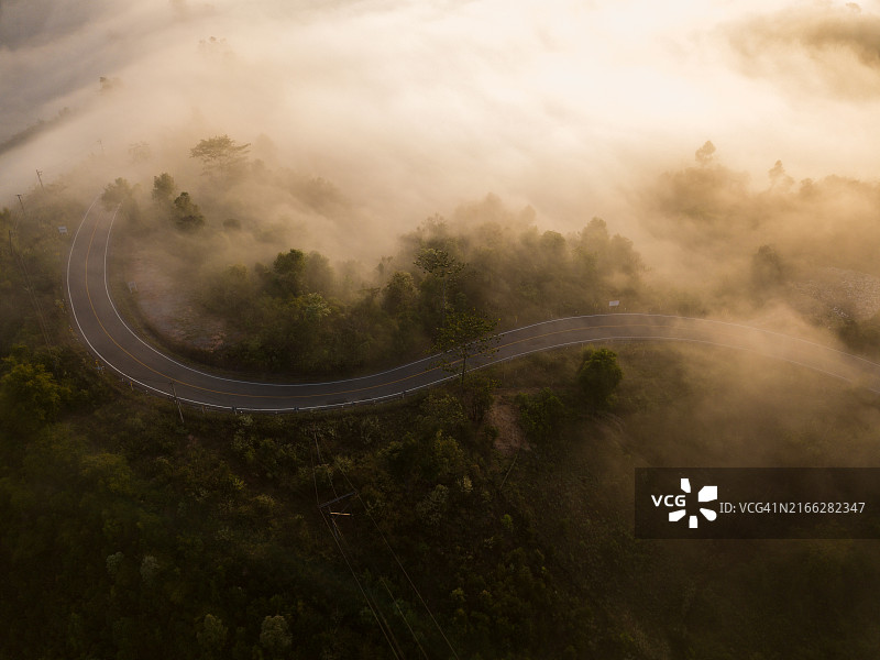 蜿蜒的道路，在清晨的浓雾中显现图片素材