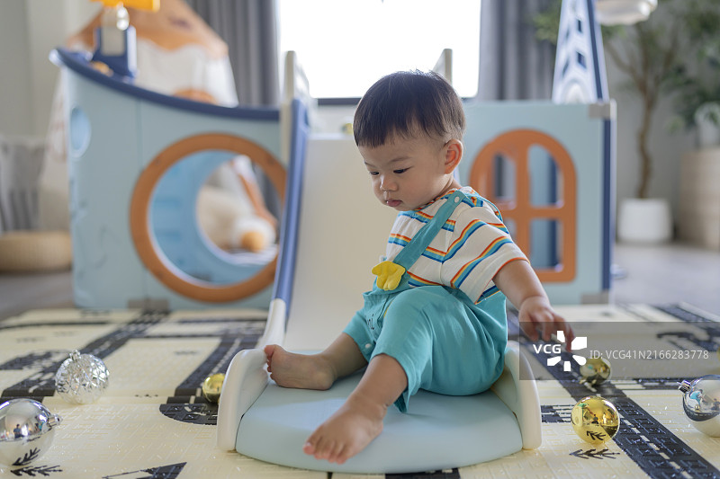 亚洲男婴在家中爬过玩具屋隧道滑梯图片素材