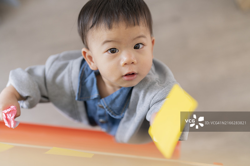 好奇的亚洲宝宝在黑板上玩便签纸，享受快乐居家生活图片素材