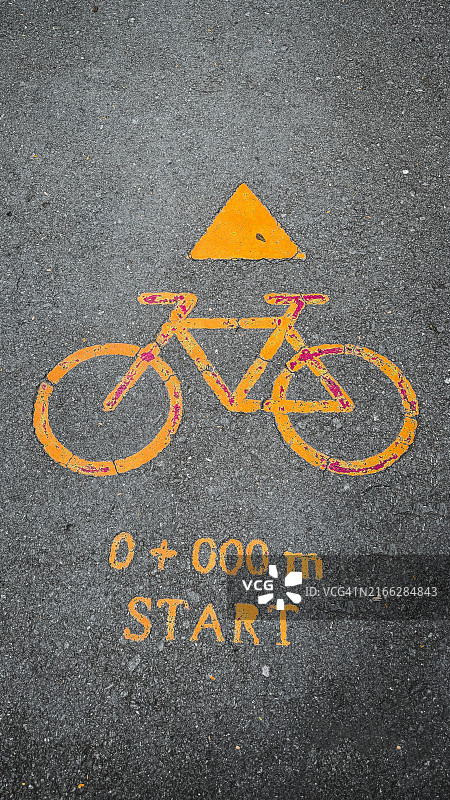 沥青路面上标有黄色自行车标志的自行车道，三角形和文字指示路线起点图片素材