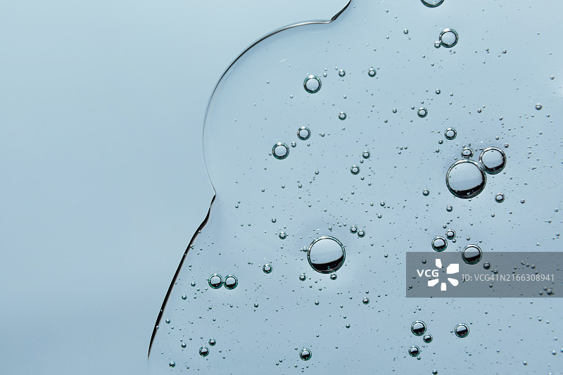 浅蓝色背景上的透明气泡凝胶霜：液态透明质酸凝胶，俯视图图片素材