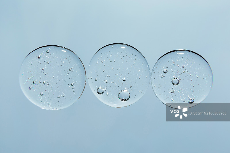 蓝色背景上带有气泡的透明水滴和凝胶涂抹图片素材