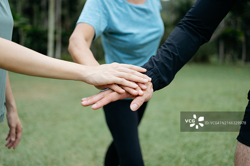 在公共公园里，互相支持的陌生成年人将手放在一起。图片素材