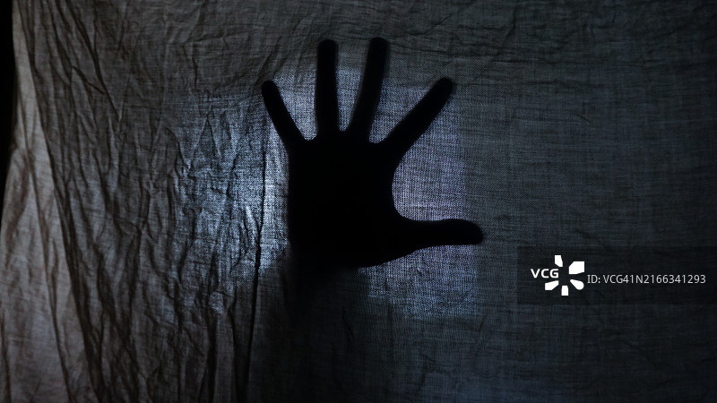 昏暗灯光下，毯子中手掌的轮廓图片素材