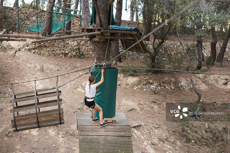 年轻女子在户外探险公园享受滑索图片素材