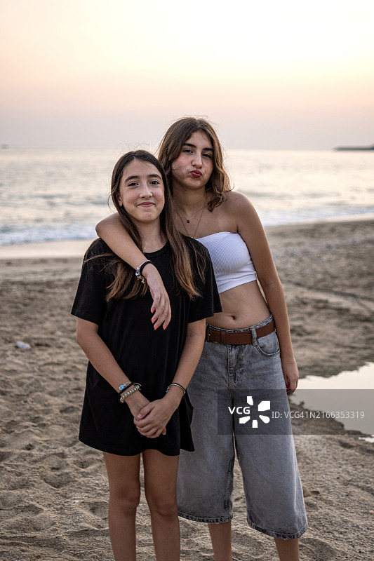 在海滩边为朋友摆姿势的漂亮少女图片素材