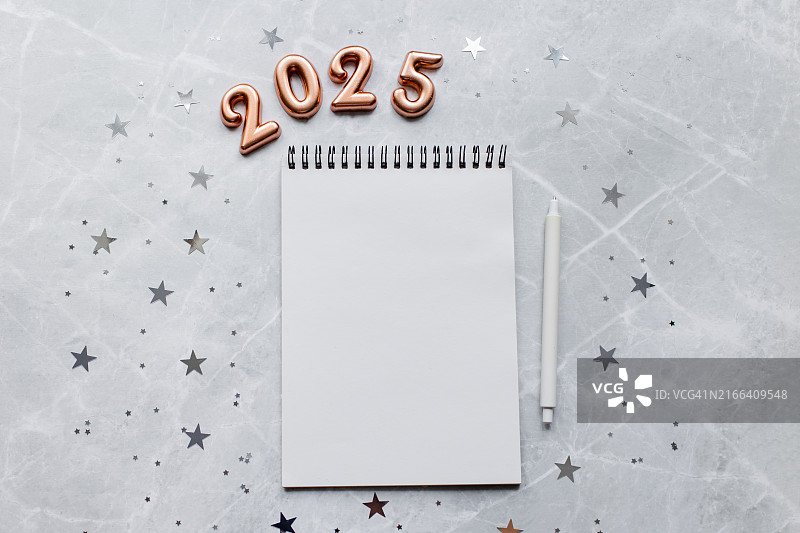 白色大理石桌面上的空白记事本、笔和2025数字新年计划概念图片素材