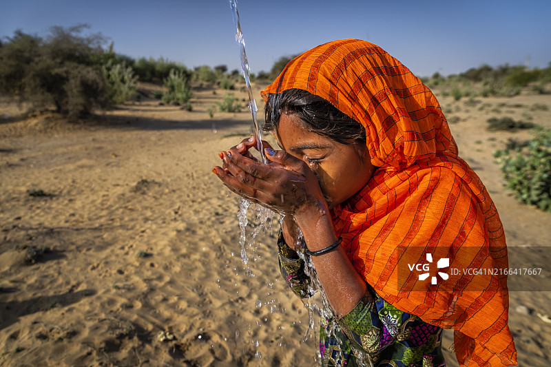 印度拉贾斯坦邦沙漠村庄饮用淡水的年轻女孩图片素材