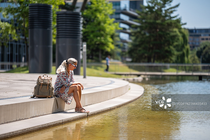 坐在城市池塘边的夏装女子图片素材