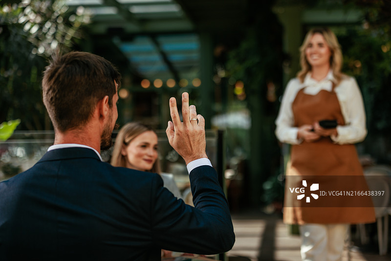 一名男子呼唤女服务员的背影图片素材