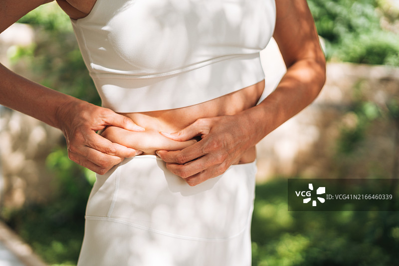 穿着运动服的年轻女人捏着腰间的赘肉图片素材