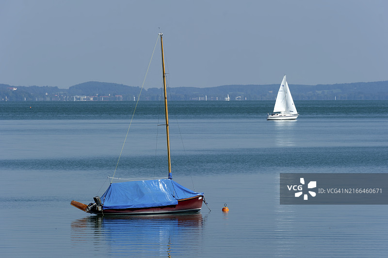 德国上巴伐利亚州施塔恩贝格湖上平静水面上的帆船图片素材