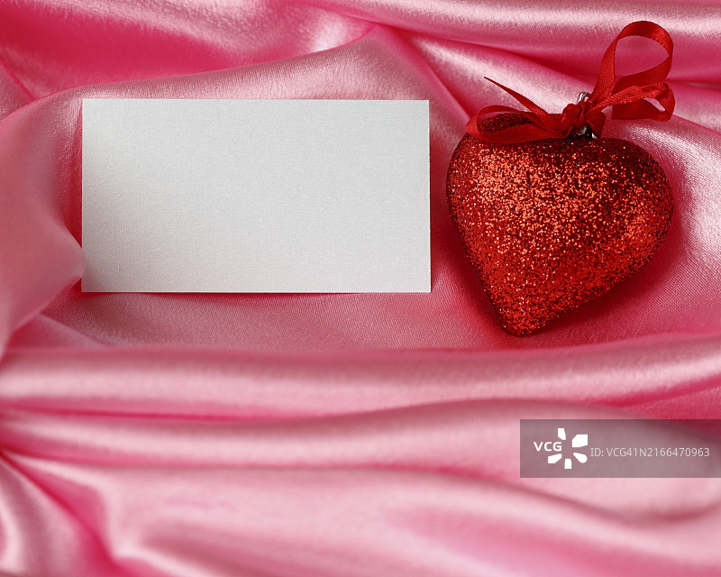 粉色缎面上的情人节贺卡、心形和空白图片素材