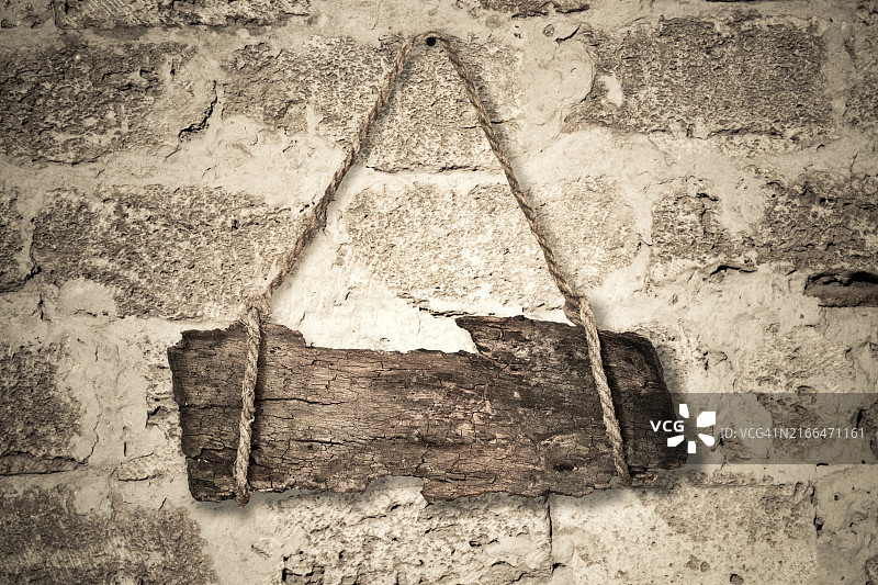 悬挂在石墙上的老式木制标志图片素材