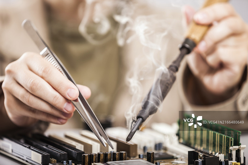 工人手持烙铁维修电脑电路板图片素材