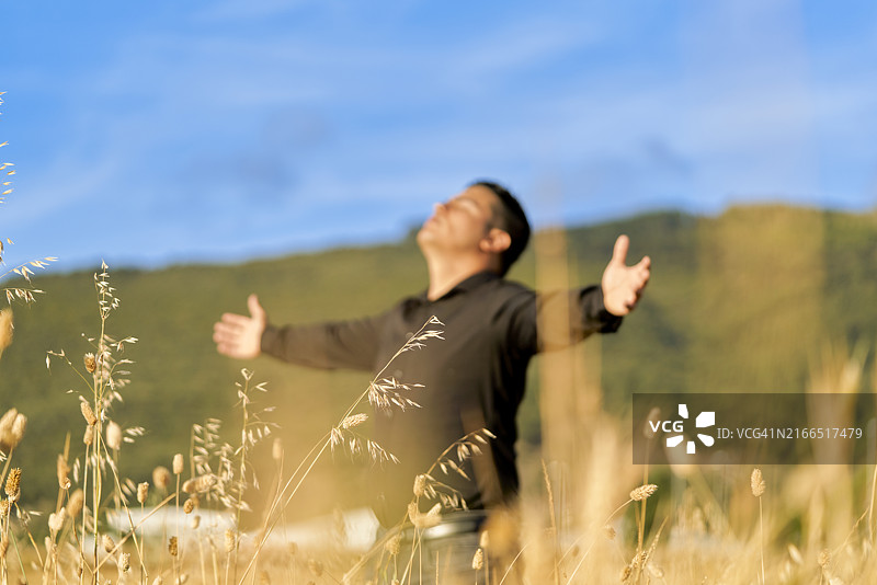 一名身穿黑色衣服，闭着眼睛，低着头，张开双臂的男人正面图图片素材